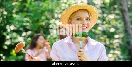 Ragazza trattiene le forcelle con salsiccia e il cetriolo. Nutrizione alternativi per vegetariani. Stile di vita vegetariano è la sua scelta. I vegetariani scelta nutrizionale. Scelta a base di carne o verdure. Lei preferisce vegetali. Foto Stock