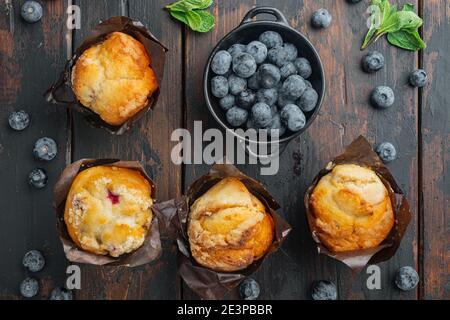 Muffin ai mirtilli con berrie fresca, su vecchio sfondo di legno scuro, vista dall'alto piatto Foto Stock