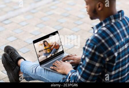 Giovane ragazzo nero che ha una lezione di musica on-line sul computer portatile all'aperto, spazio di copia Foto Stock