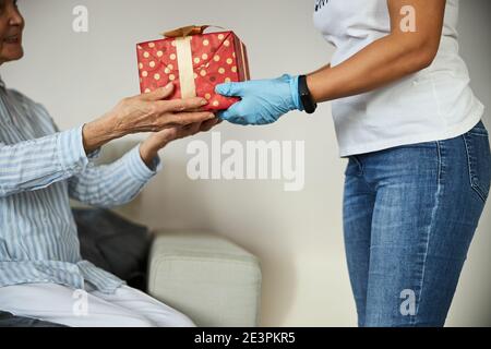 Persona che passa un pacchetto di compleanno a una vecchia donna Foto Stock