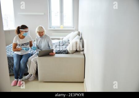 Volontario femminile che mostra come usare un Internet Foto Stock