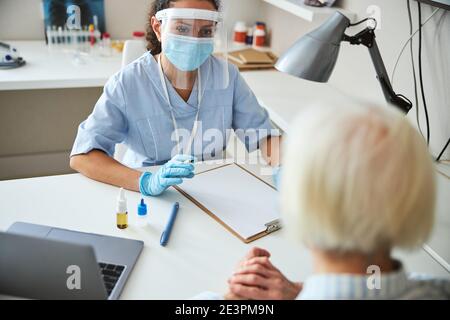 Medico che guarda con interesse ad un cliente anziano Foto Stock