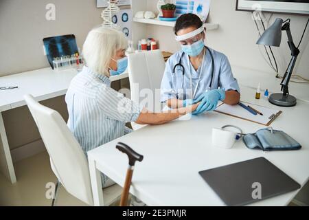 Un medico attento tocca il polso della donna anziana con due pollici Foto Stock