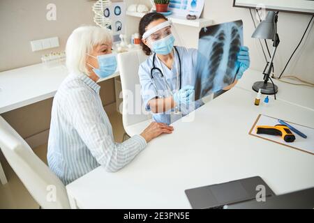 Medico donna professionale sollevamento di una radiografia in aria Foto Stock