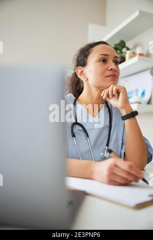 Specialista medico che si proppa il mento mentre scrive Foto Stock