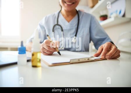 Penna ecologica nelle mani di un medico che scrive su carta Foto Stock