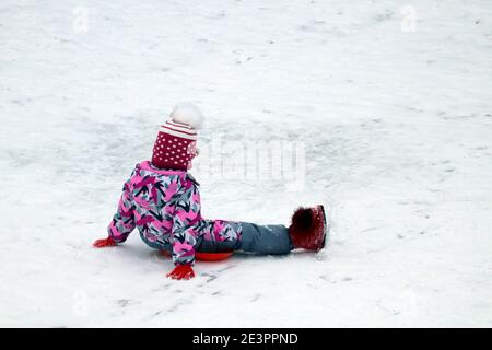 Bambini che cavalcano su un vassoio, slittino invernale. Bambina che scende lungo la collina della neve Foto Stock