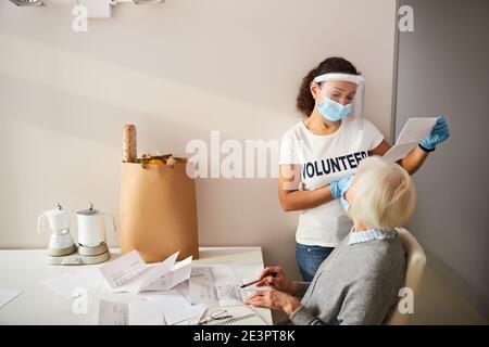 Due donne in maschere di faccia che si occupano di bollette di utilità Foto Stock