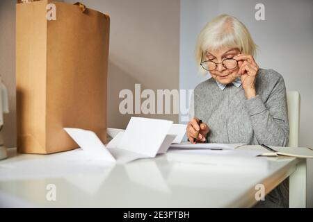 Pensionato con una penna in mano che esamina i documenti Foto Stock