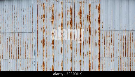 Parete bianca e arrugginita di hangar industriale in corrugato lamiera d'acciaio - sfondo astratto Foto Stock