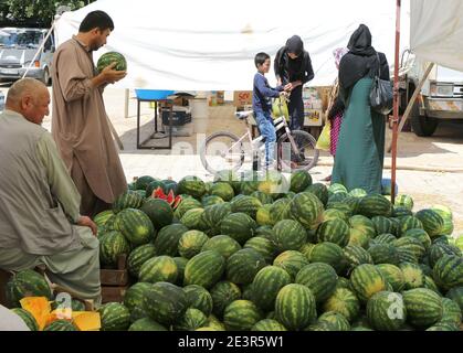 OVAKENT, HATAY, TURCHIA-GIUGNO 3: Uomo Uzbeko scelta di un melone maturo al mercato contadino.Giugno 3,2017 in Ovakent, Hatay, Turchia. Foto Stock