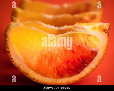 Sfondo di frutta colorato. Le fette di arancio rosso sono su sfondo arancione luminoso. Agrumi freschi ricchi di vitamine, frutta succosa, alimentazione sana. Foto Stock