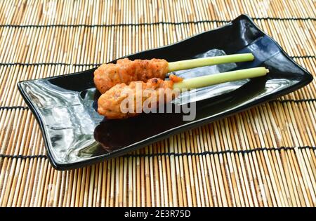 pollo arrosto fermentando polvere curcuma stabbing in erba di limone su piastra Foto Stock