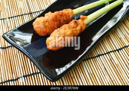 pollo arrosto fermentando polvere curcuma stabbing in erba di limone su piastra Foto Stock