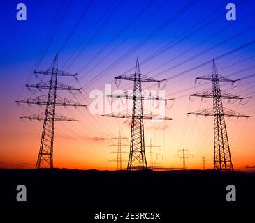 Tralicci elettrici, torri di trasmissione che si stagliano all'alba del tramonto per la copia Foto Stock