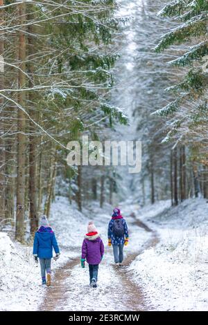 Madre e bambini che si godono una passeggiata attraverso il bosco insieme in inverno, Bialowieza Forest, Polonia Foto Stock