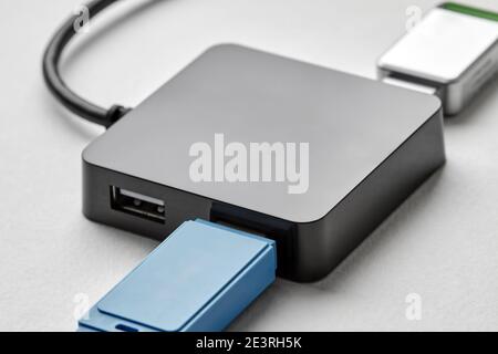 Hub USB portatile nero per quattro connessioni con unità flash usb su sfondo bianco. L'autobus era povero. Primo piano, messa a fuoco selettiva. Foto Stock