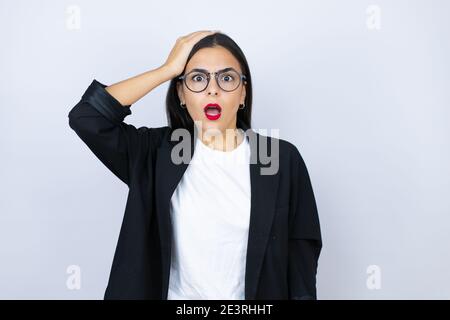 Bella donna di affari che mette una mano sulla sua testa sorridente come lei aveva dimenticato qualcosa Foto Stock