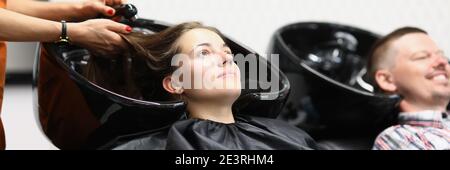 Un impiegato del salone lava i capelli alla donna nel lavandino Foto Stock