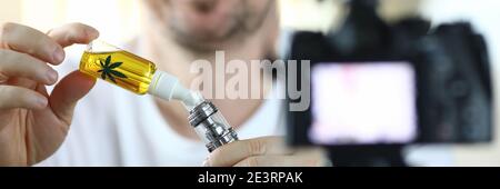 Il ragazzo di fronte alla fotocamera riempie un vape Foto Stock