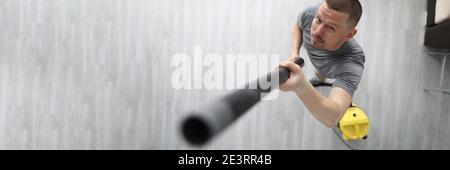 Un uomo raccoglie la polvere con il tubo dell'aspirapolvere Foto Stock