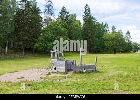 Vista del paesaggio naturale con la nave da gioco in legno abbandonata su verde foresta alberi sfondo. Svezia. Foto Stock