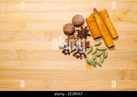 Diverse spezie sfondo che includono cannella, cardamomo, chiodo di garofano, pepe nero, Nutmeg, anice stella sullo sfondo di legno con spazio di copia. Foto Stock