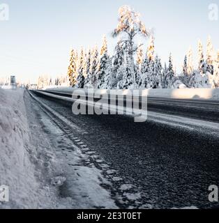 Strada invernale ghiacciata con asfalti scuri. Sfondo sfocato. Foto Stock