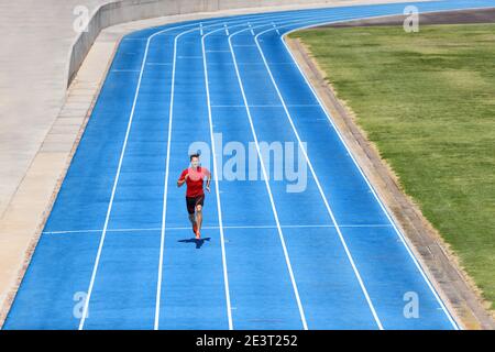 Atleta di Sprinter Runner che si sprint su piste all'aperto e piste da corsa allo stadio. Allenamento sportivo e sanitario attivo su piste blu. Foto Stock