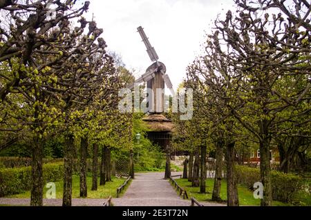 Percorso tra alberi verdi con un vecchio legno storico mulino in background Foto Stock