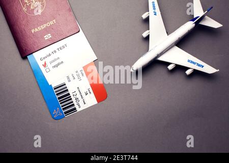 Viaggio durante la pandemia COVID-19, passaporto con biglietto aereo, test positivo covid-19 e aereo su sfondo grigio, salute della sicurezza dell'aeroporto e saf Foto Stock