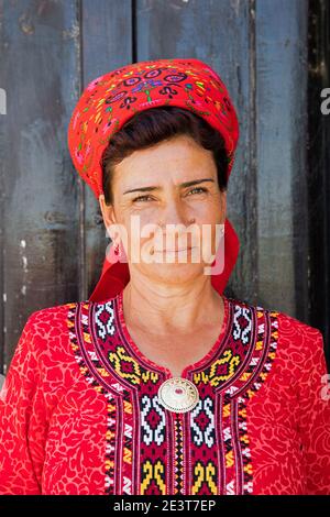 Primo piano ritratto di donna turkmeno con foulard rosso e koynek, abito lungo tradizionale con ricamo, Turkmenistan Foto Stock