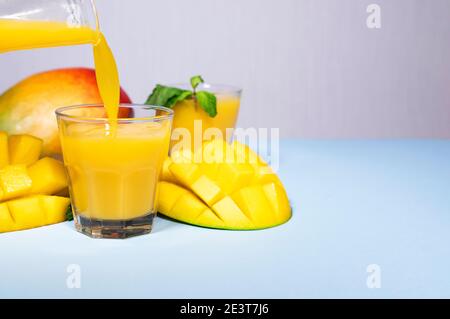 Mango Shake su sfondo blu. Sano bere Vitamina Smoothie. Succo fresco di frutta tropicale di mango. Spazio per testo, CopySpace. Cibo da dieting Foto Stock