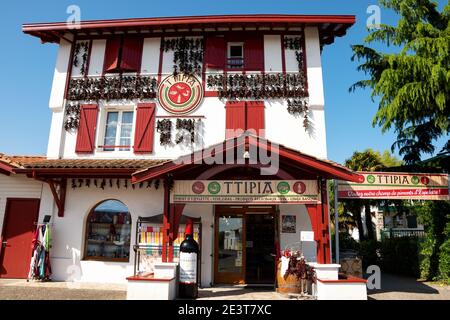 ESPELETTE, FRANCIA - AVRIL 19, 2018: Negozio di delicatessen situato in un tradizionale edificio basco dipinto di bianco rosso decorato con espelette pe asciutto appeso Foto Stock