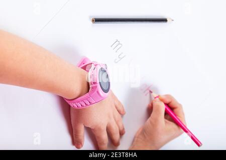 Le mani dei bambini scrivono con matite la parola il mio orologio su uno sfondo bianco. Foto Stock