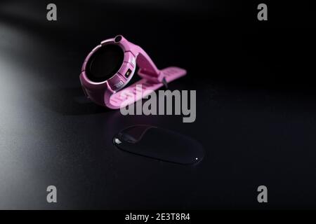 orologio intelligente impermeabile rosa con gocce d'acqua su sfondo nero. Foto Stock