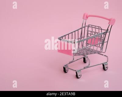 Piccolo carrello vuoto della spesa su sfondo rosa Foto Stock