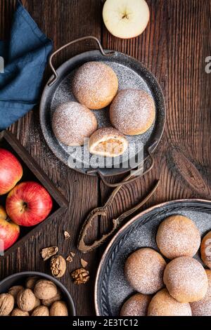 Deliziosa pasticceria dolce, ciambelle al forno con ripieno di mela e noce, cosparse di zucchero in polvere Foto Stock