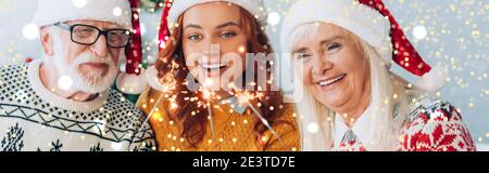 orientamento panoramico di felice coppia senior con figlia che tiene sparklers a natale, bokeh luci illustrazione Foto Stock