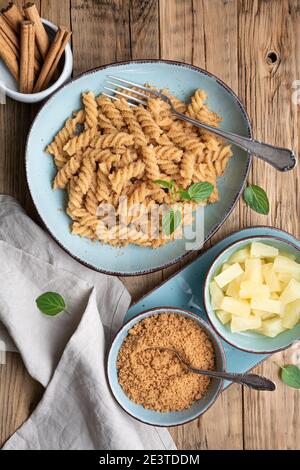 Semplice pasta di fusilli con semola e cannella dolci arrostite, servita con pezzi di ananas Foto Stock