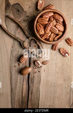 Snack sano ricco di vitamine e minerali, noci pecan sgusciate fresche in una ciotola su sfondo di legno con spazio per la copia Foto Stock