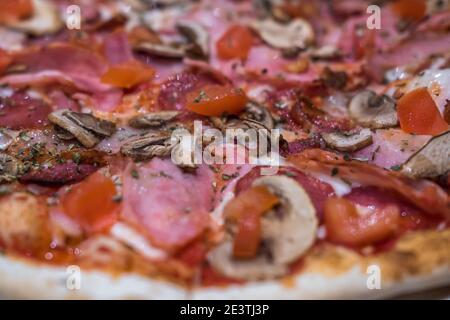 Deliziosa pizza classica italiana Carbonara con prosciutto, pomodori, funghi e formaggio Foto Stock