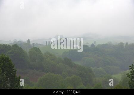 Misty mattina paesaggio nei Paesi Baschi francesi. Tradizionale casa colonica e colline che si nascondono nella nebbia. Foto Stock