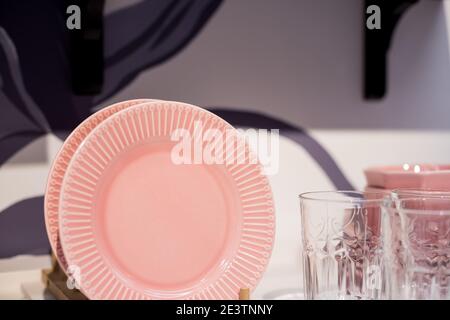 Piatti commerciali rosa e bianco e ciotole impilate con cristallo Vino calici. Ceramica colorata piatti puliti.Ceramica stoviglie stoviglie stoviglie stoviglie stoviglie Foto Stock
