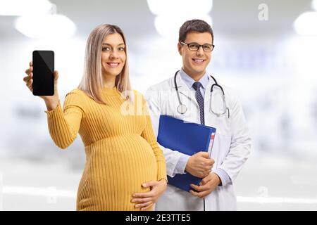 Medico maschile e una donna incinta sorridente che tiene un cellulare telefono Foto Stock