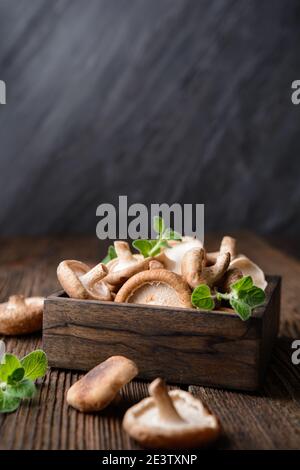 Un mucchio di immunità che aumenta i funghi Shiitake freschi in una ciotola su sfondo rustico in legno con spazio copia Foto Stock