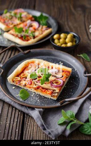 Pizza di funghi Shiitake sana e fatta in casa con fette di olive verdi, formaggio, cipolla rossa e origano su rustico fondo di legno Foto Stock