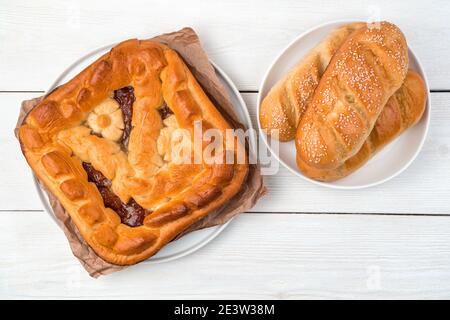 Pasticcini freschi, torta di mele e panini su uno sfondo chiaro. Vista dall'alto, con uno spazio per la copia. Foto Stock