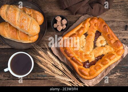 Torta di mele, panini freschi e spikelets di grano e una tazza di tè su sfondo di legno marrone. Foto Stock