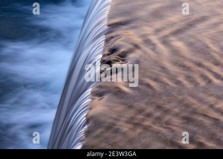 Streaming con una cascata al tramonto. Vista dall'alto. Breve tempo di esposizione che mostra il movimento. Acqua sfocata. Foto Stock